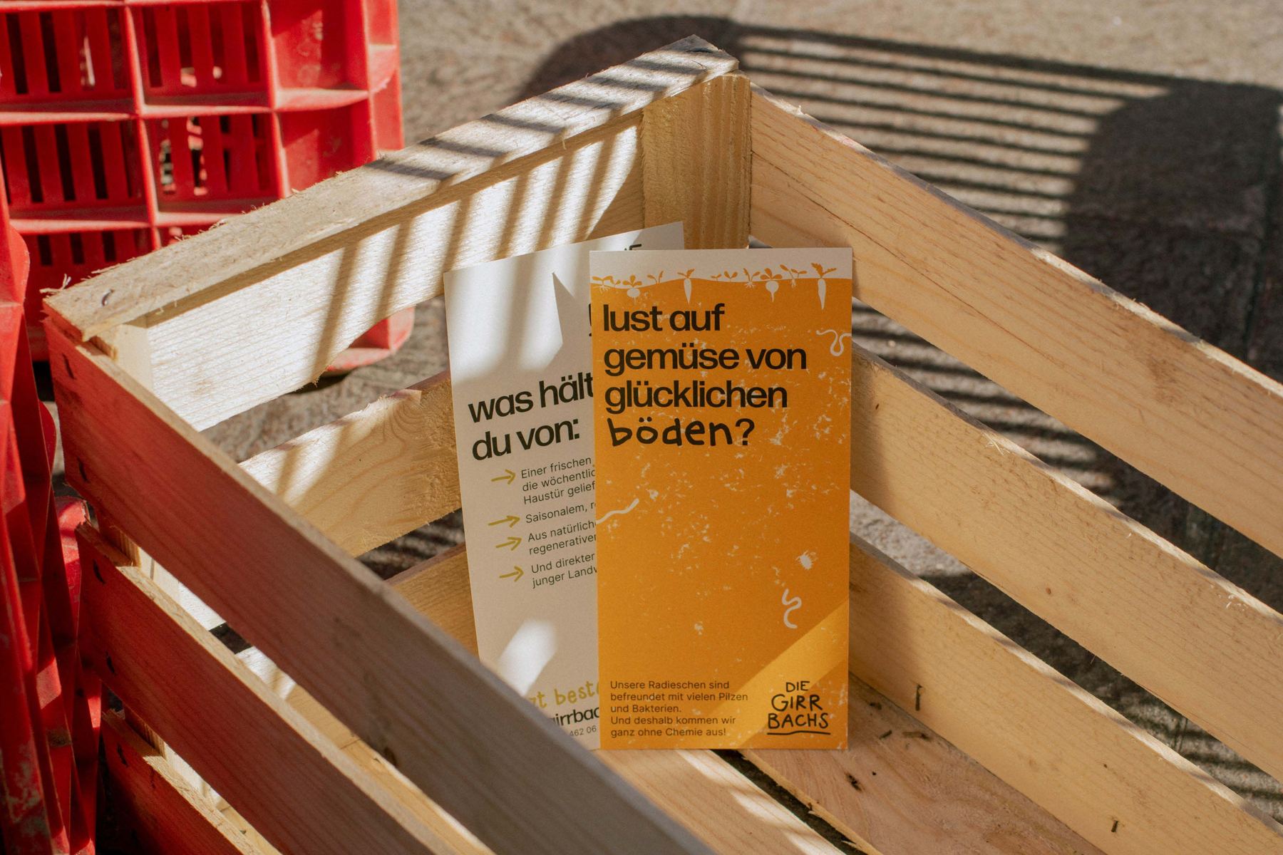 Faltflyer „lust auf gemüse von glücklichen böden?“ in einer Holzkiste